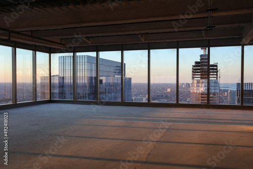 Two high-rise buildings visible through floor to ceiling windows of tall and empty skyscraper in urban area