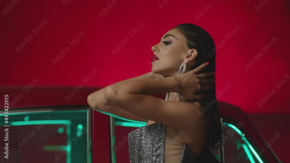 Beautiful Elegant Young Woman Standing , Dancing and Flirting near old retro classic car. Old fashioned luxury style concept . Rich fashion lifestyle . Luxury dress with fabric glitter, spangles .