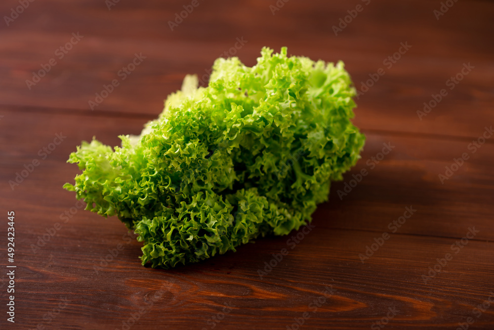 Green lettuce salad on a wooden background. Vegetarianism concept, plant food. Green lettuce salad on a wooden background. Vegetarianism concept, plant food.