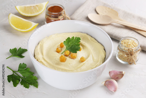 Hummus traditional middle estern sause from cheakpeas in a white bowl and ingredients. Vegan dish