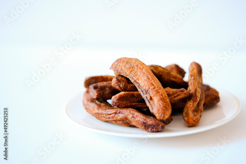 Dried bananas on a light plate. Copy space.