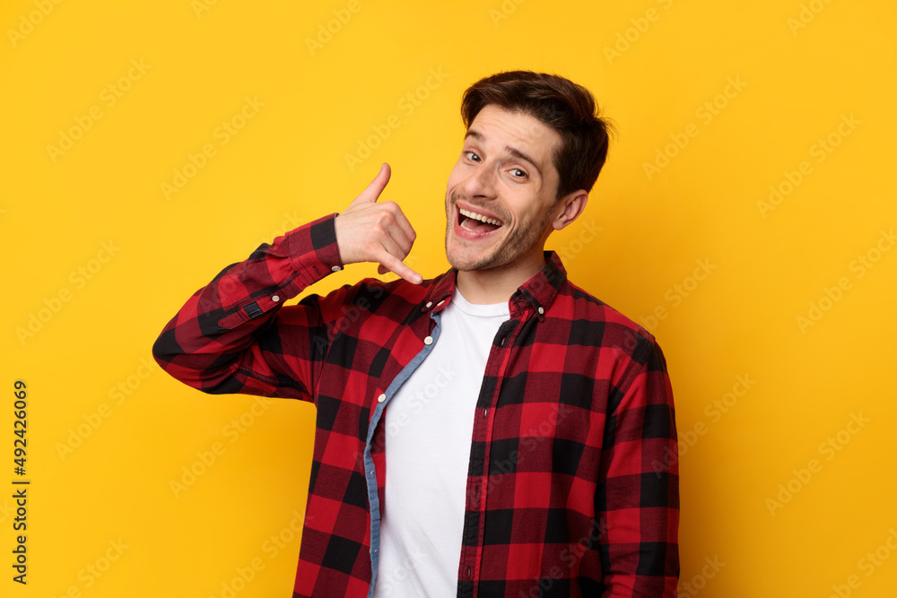 Portrait of smiling man making call me gesture Portrait of smiling man making call me gesture