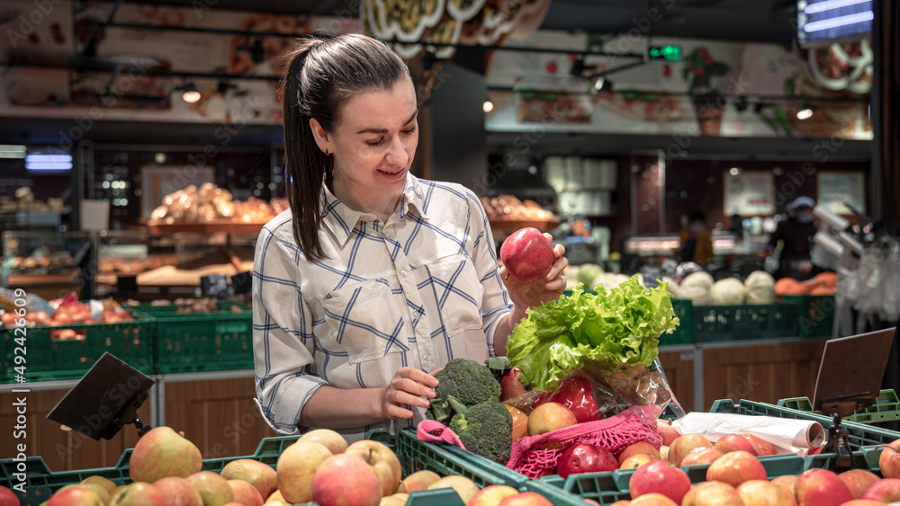 A young woman chooses fruits and vegetables in a supermarket. A young woman chooses fruits and vegetables in a supermarket.