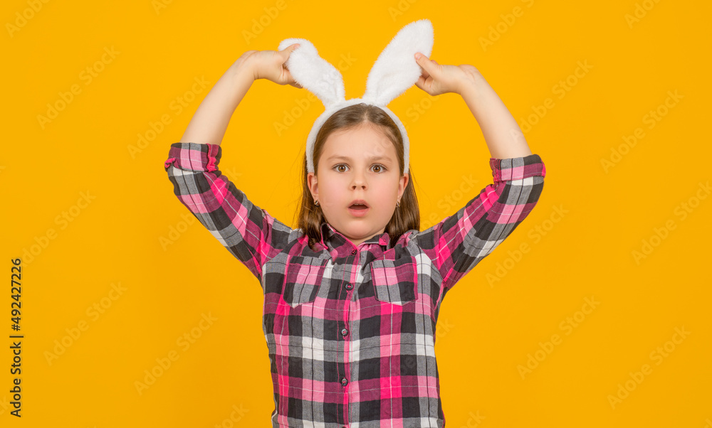 amazed easter child in bunny ears on yellow background amazed easter child in bunny ears on yellow background