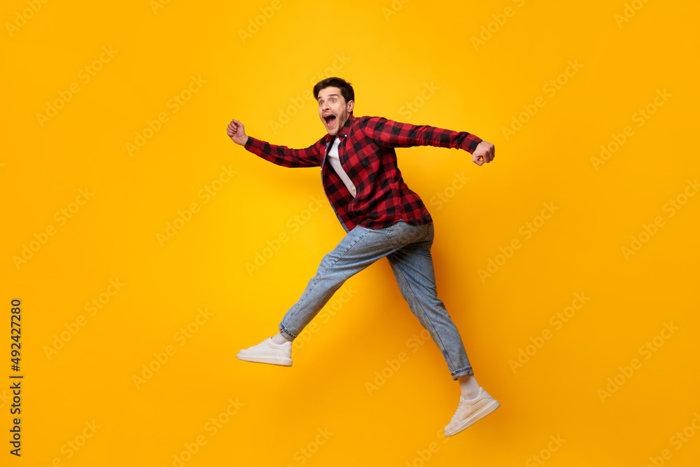 Excited young man jumping up at orange studio