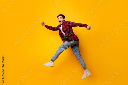 Excited young man jumping up at orange studio © Prostock-studio