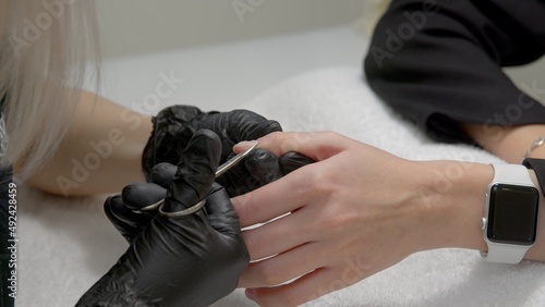 A close-up of a master doing a manicure to a young girl in a beauty salon. The concept of nails, manicure, beauty, fashion. © stanis88