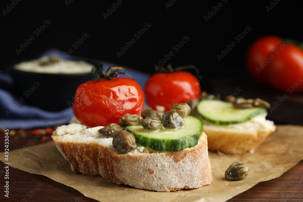 Tasty bruschettas with vegetables and capers on wooden table, closeup Tasty bruschettas with vegetables and capers on wooden table, closeup
