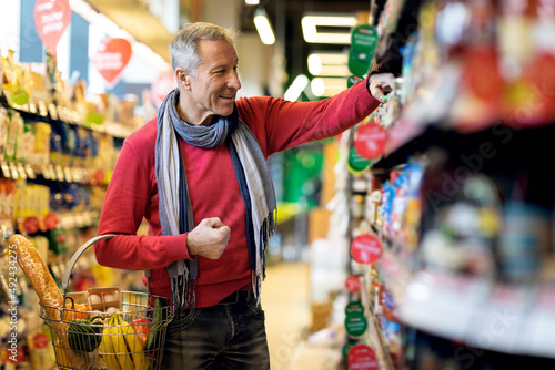 Positive attractive senior man choosing goods at store photo