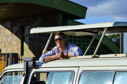 Smiling tourist (man) in sunglasses in a safari car photo