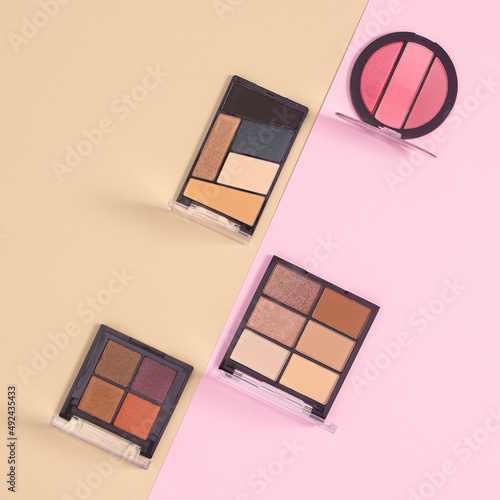 Eye shadows make up products commposition on pastel beige and pink background. Flat lay minimal skin care fashion concept photo