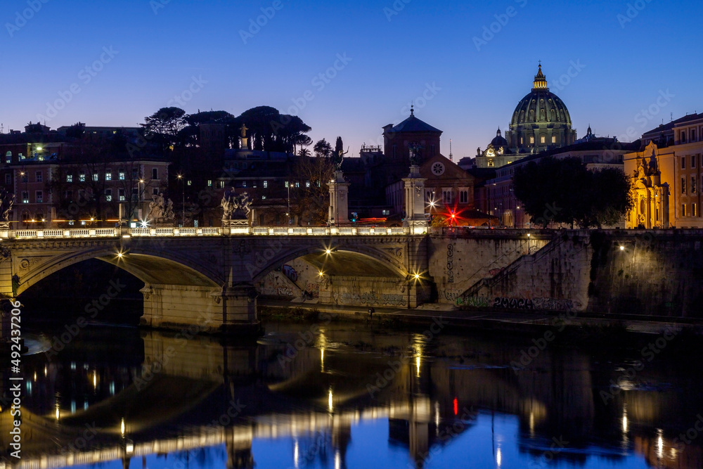 Bridge of Vittorio Emanuele II over river Tiber, and the dome of Saint Peter's Basilica at the background, in the beautiful city of Rome, Italy, Europe. 
