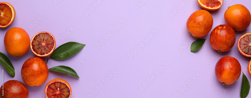Many ripe sicilian oranges and leaves on violet background, flat lay with space for text. Banner design Many ripe sicilian oranges and leaves on violet background, flat lay with space for text. Banner design