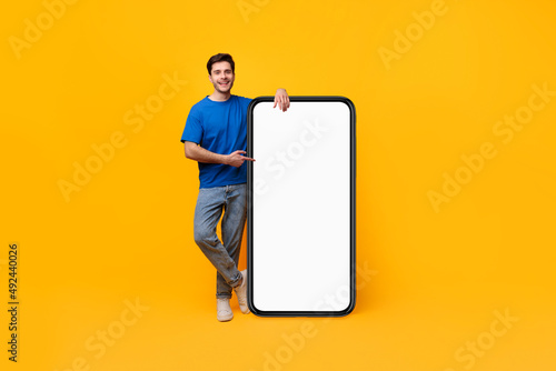 Guy pointing and leaning on big white empty smartphone screen