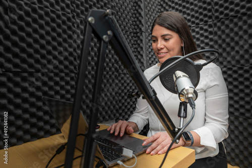woman speaks into a microphone while recording a podcast, using an audio booth with acoustic insulation