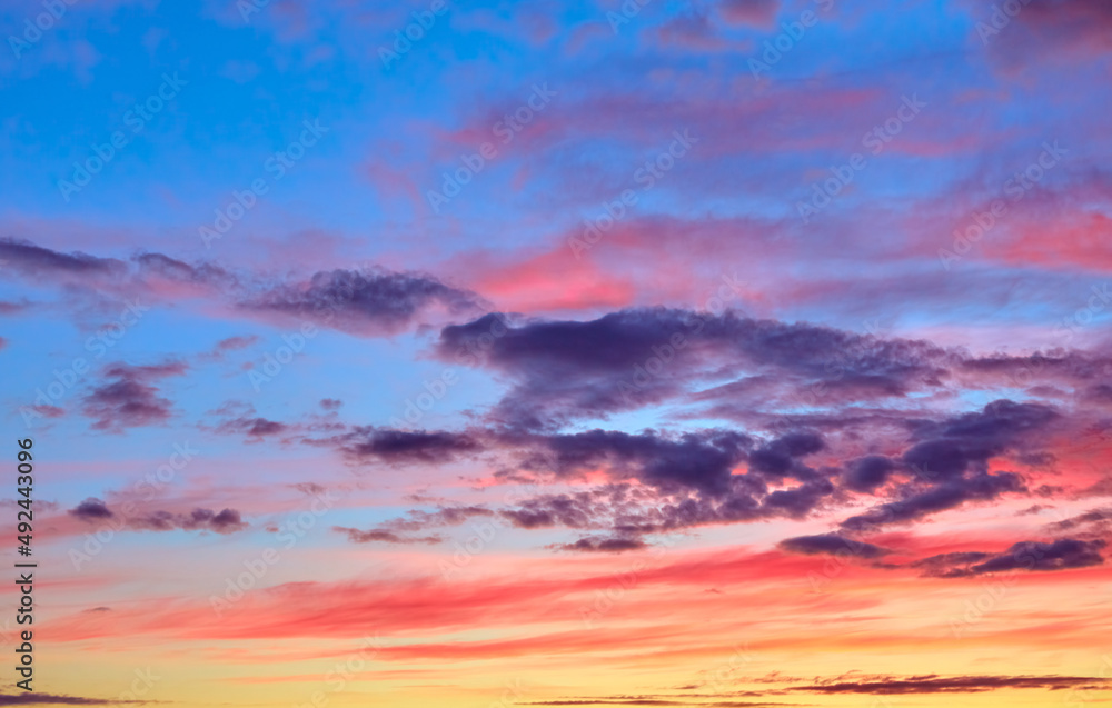 Bright colored sunset sky with colorful clouds. Abstract natural landscape. Sunny sunrise. Yellow, pink, blue and purple shades. Cloudscape. Weather forecast. Golden hour. Banner. Twilings time. Air