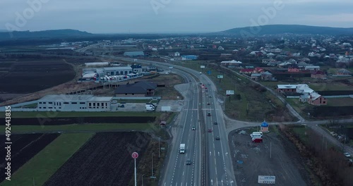 a four-lane automobile highway outside the city in a populated industrial area along which a stream of cars travels. drone view