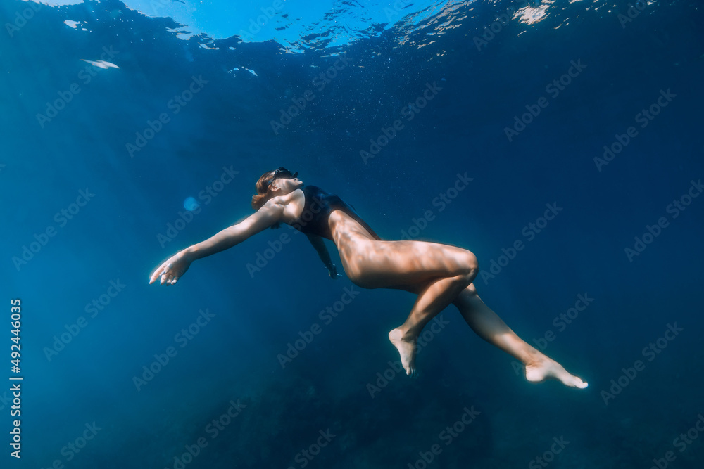 Woman posing underwater in ocean. Freediving and beautiful lady