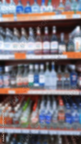 Abstract blur image of supermarket background. Defocused shelves with bottles of alcohol, vodka, cognac, brandy, wine, beer, champagne. Grocery Store. Retail industry. Inflation and crisis concept.