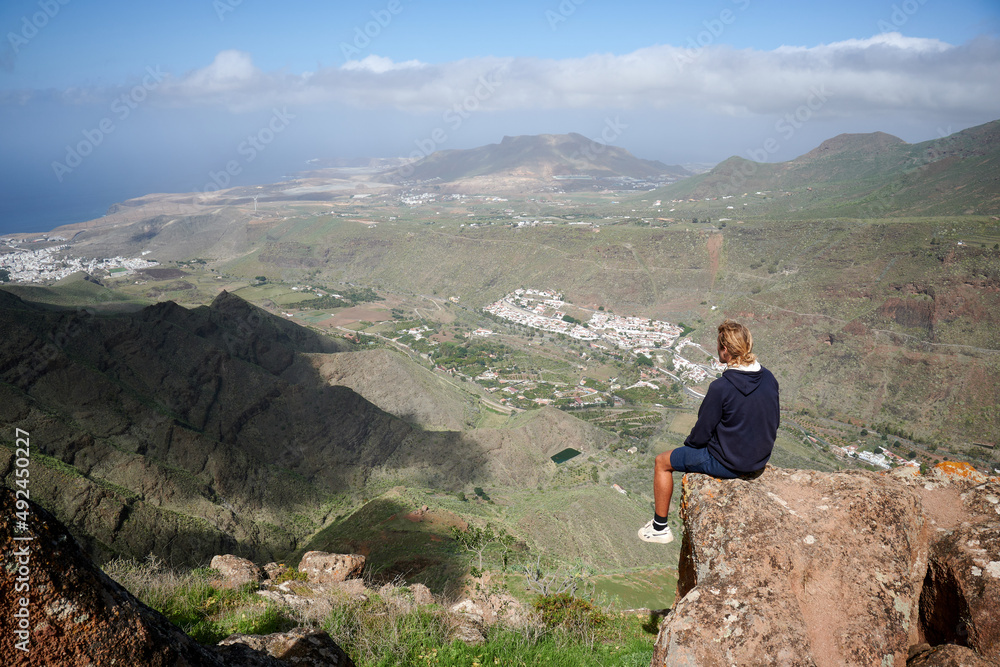A young man sitting on a rock admiring the beautiful views in the mountains in Gran Canaria