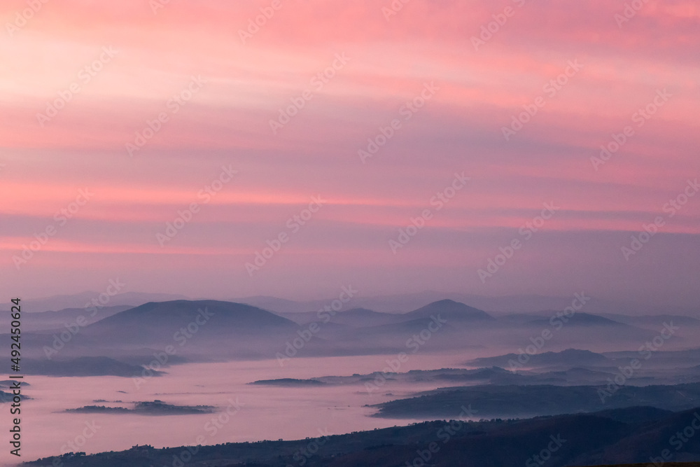 Mist and fog between valley and layers of mountains and hills at sunset, in Umbria Italy