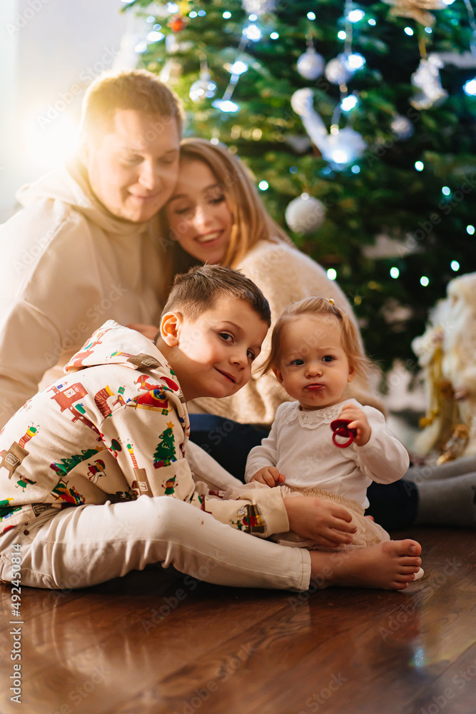 a happy family with two small children at home by the Christmas tree. a happy family with two small children at home by the Christmas tree.