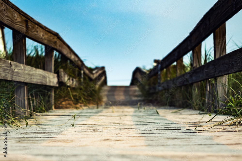 A textured wooden path leading away from the beach into a beautiful blue sky A textured wooden path leading away from the beach into a beautiful blue sky