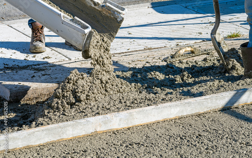 Wet Cement or concrete being poured out of a cement truck onto a construction site forming a sidewalk.