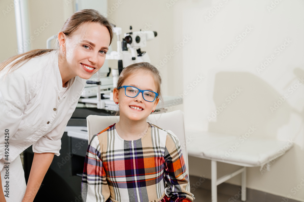 ophthalmologist picks up glasses for a little girl at an appointment in a clinic ophthalmologist picks up glasses for a little girl at an appointment in a clinic