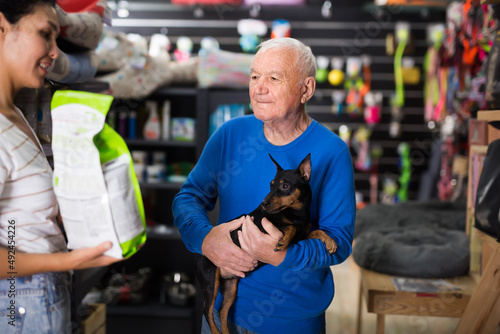 Pet store employee helps an elderly man choose dry dog food