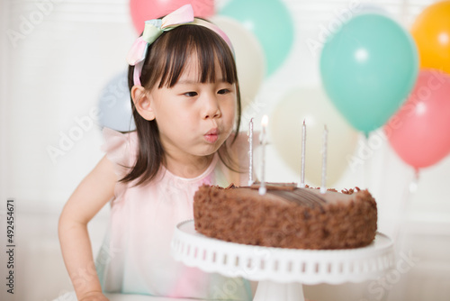 young girl blowing candles for celebrating her 4th years birthday