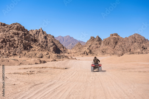 Mountains landscape and person on motorbike. Quadricycle safari park in Egypt sand desert. Sharm el Sheikh, Sinai peninsula. Extreme travel on all-terrain vehicle.
