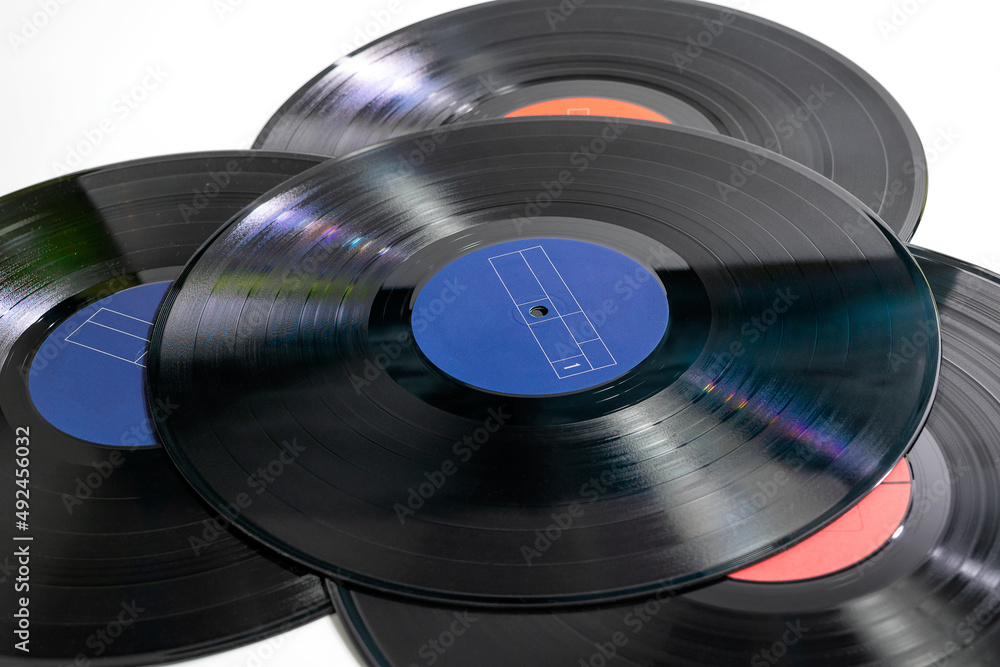 Stack of four traditional glossy black vinyl records without scratches on a white table Stack of four traditional glossy black vinyl records without scratches on a white table
