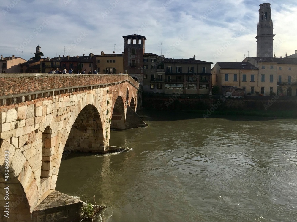  Verona, Italy. 
Verona old town view, Ponte Pietra (bridge) and Cathedral. Old stone bridge above Adige river. Cityscape, towers, shades.
