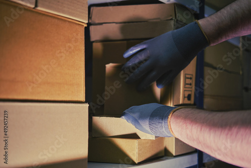 A man in gloves steals goods from a box in a warehouse. Problems with theft and security in the office