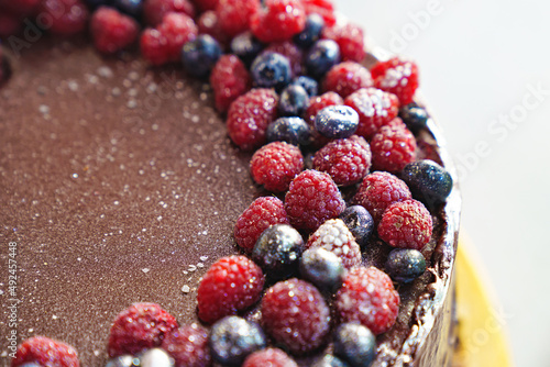 part of a round chocolate cake with fresh raspberries and blueberries