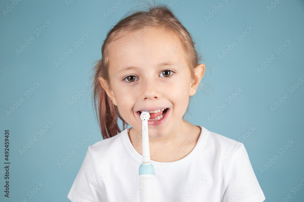 Smiling little caucasian girl brushing teeth Standing Over blue Background Smiling little caucasian girl brushing teeth Standing Over blue Background