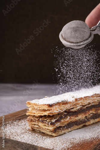 Chocolate millefeuille with sugar falling on it. photo