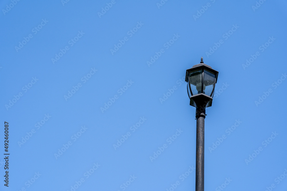 a black metal light lantern on a pole with a blue sky in the background