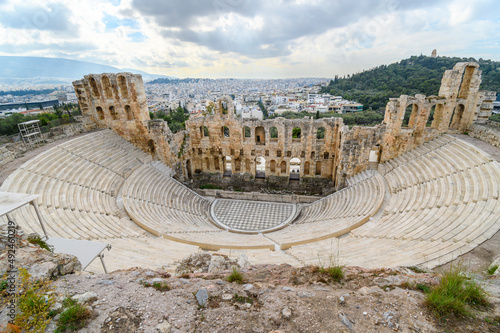 Full view from above of the Odeon of Herodes Atticus, the ancient amphitheater at the south base of Acropolis Hill, with the modern city of Athens, Greece in view behind.