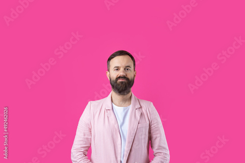 Handsome man with a beard in a pink jacket is thinking over an isolated red background. © Mountains Hunter