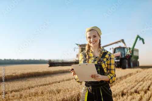 фотографія Farmer on grain field with tractor and combine harvester in background taking no
