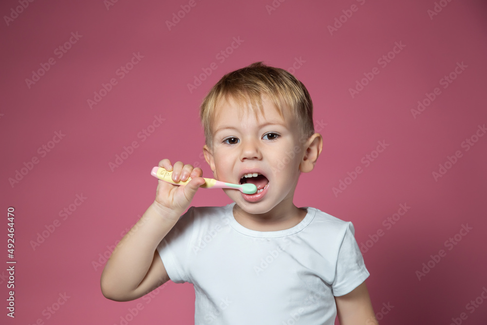 Smiling caucasian little boy cleaning his teeth with manual children toothbrush Smiling caucasian little boy cleaning his teeth with manual children toothbrush