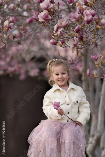 A girl with a magnolia blooming tree on the background