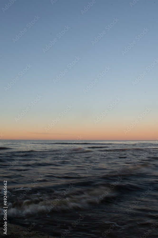 Obraz premium Sunset on the sea. Dark waters and blue sky