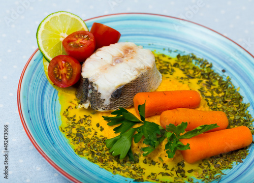 Recipe of steamed merluccius with vegetable pate: carrots, onion, garlic fry in dry frying pan, beat in blender with olive oil and salt. 250g of fish steam for 15min. Serve with fresh herbs and lemon photo