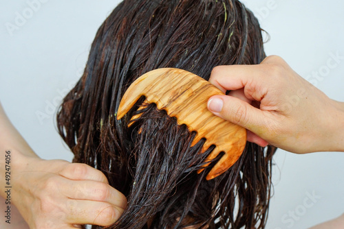 Foto Woman combing hair treatment through hair.