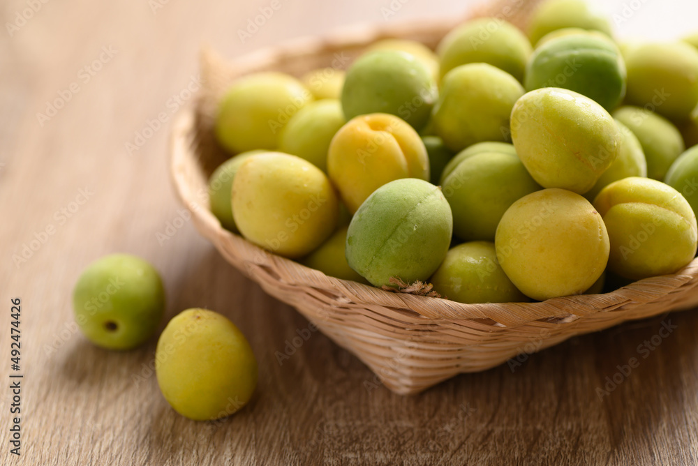 Apricot green with yellow (Japanese apricot) in basket on wooden background Apricot green with yellow (Japanese apricot) in basket on wooden background