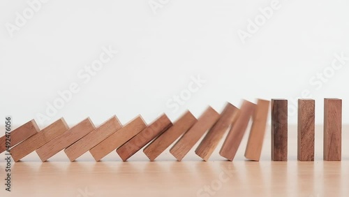 Slow motion, Domino effect made up from wooden blocks shape toy on wooden desk, domino effect in business concept,  Risk protection concept. photo