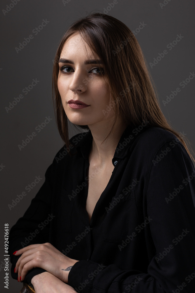 Portrait of a young brunette with long hair in the studio. Dramatic photo in dark colors. Portrait of a young brunette with long hair in the studio. Dramatic photo in dark colors.